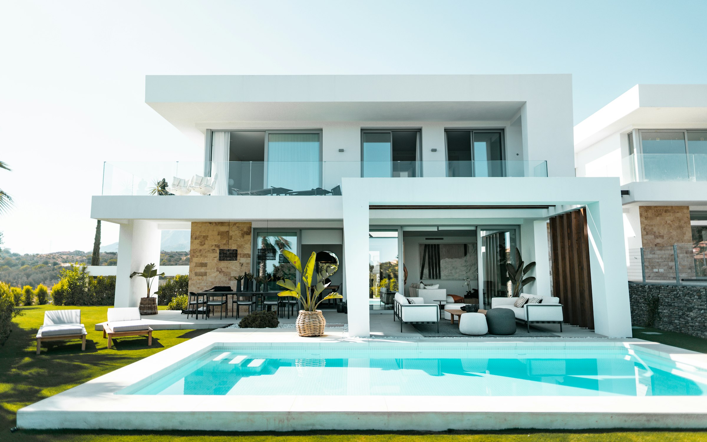 White contemporary villa with a pool terrace stepping down a sloped site.