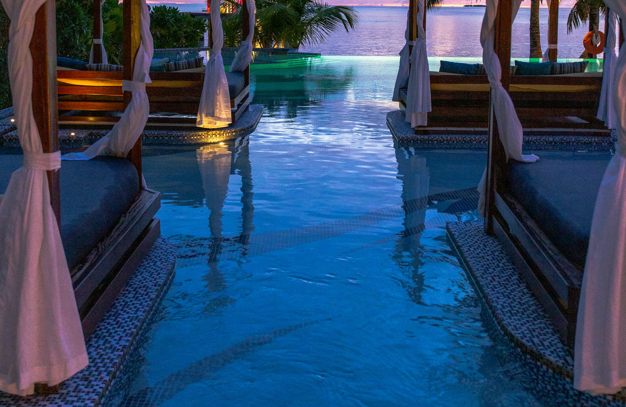 Poolside terrace at dusk within a landscaped courtyard.
