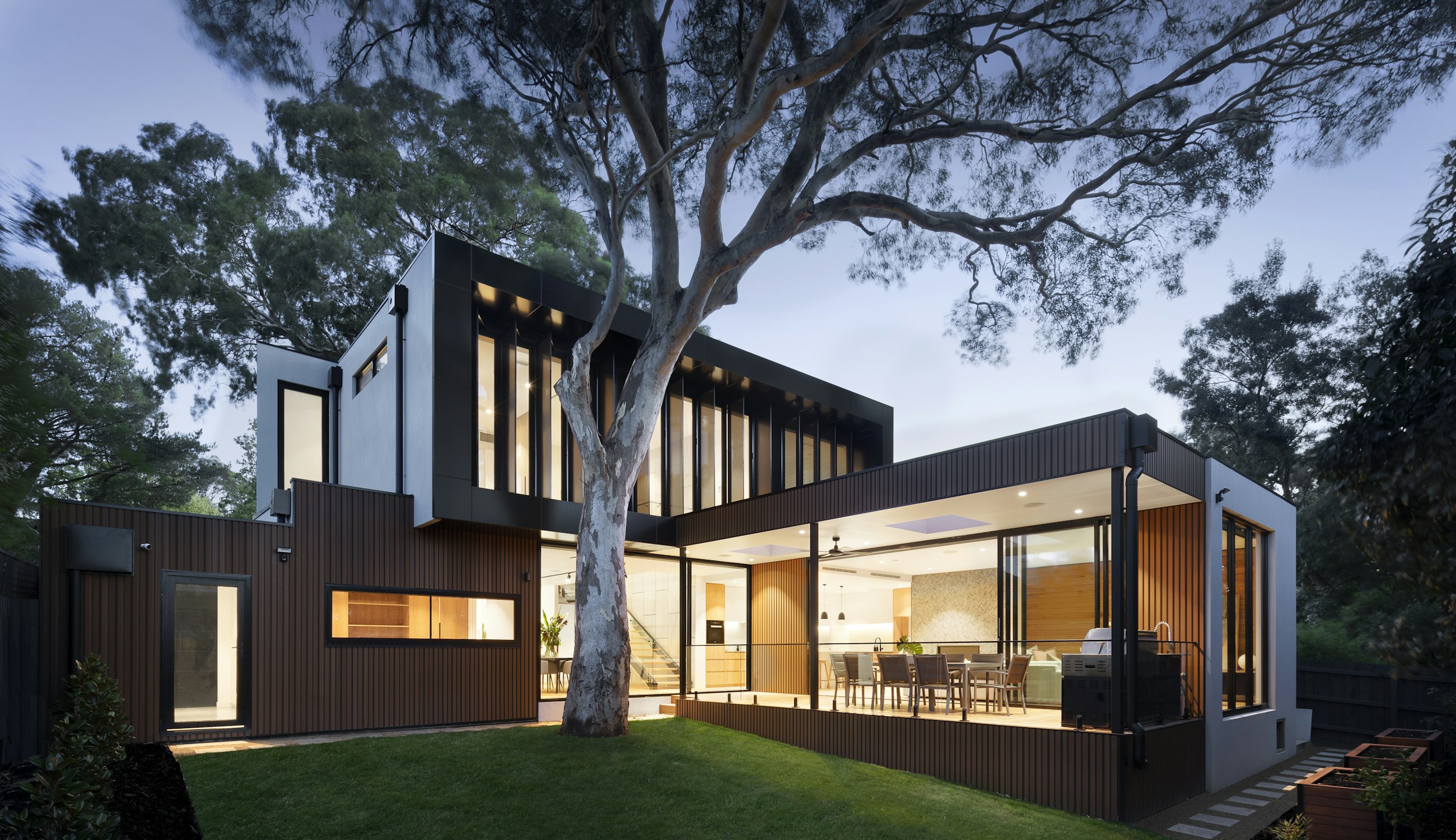 Contemporary residence at dusk, its landscape, terrace and lighting designed as one connected environment.