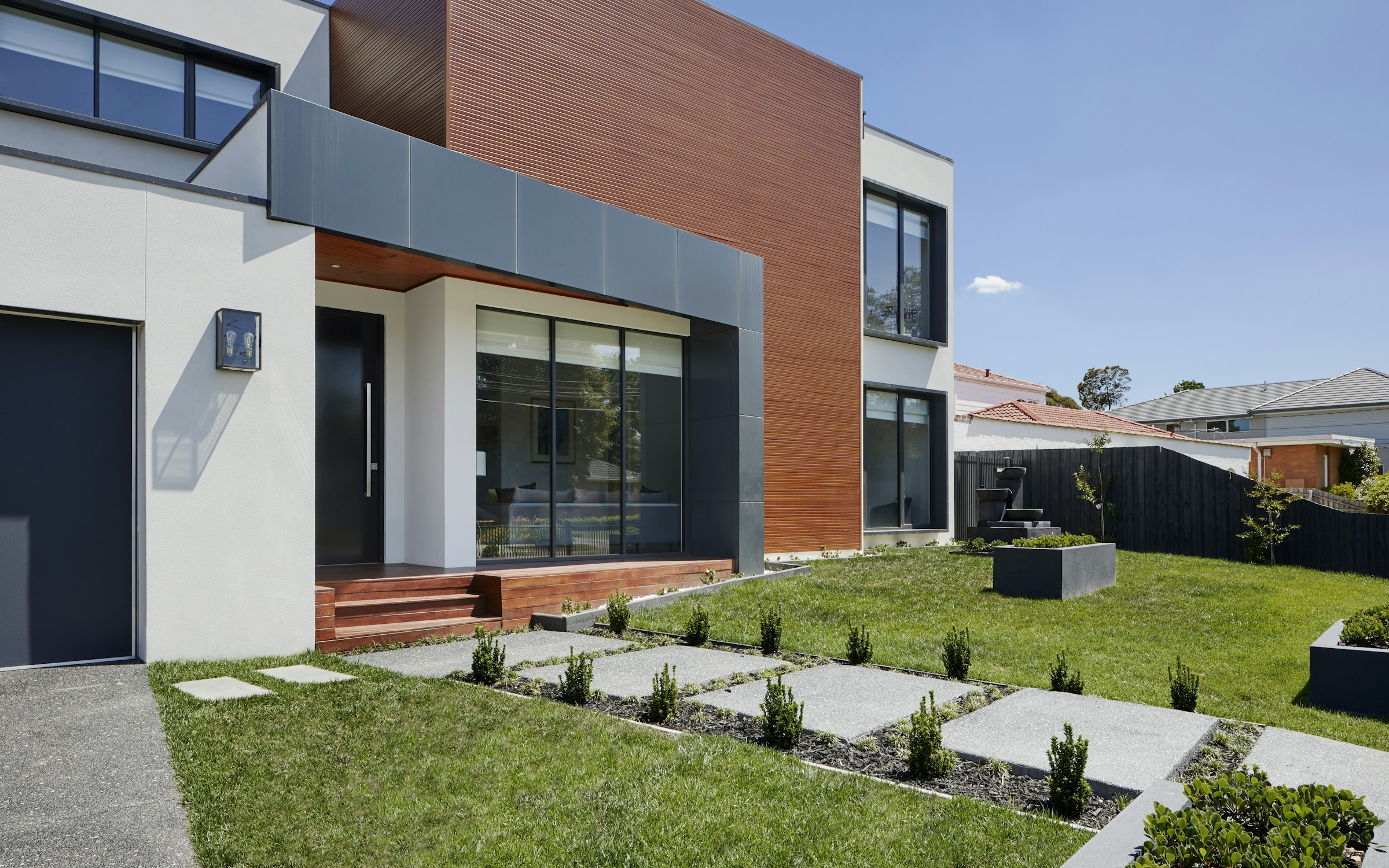 Wood-clad pavilion set among stepping-stone paving and mature planting.