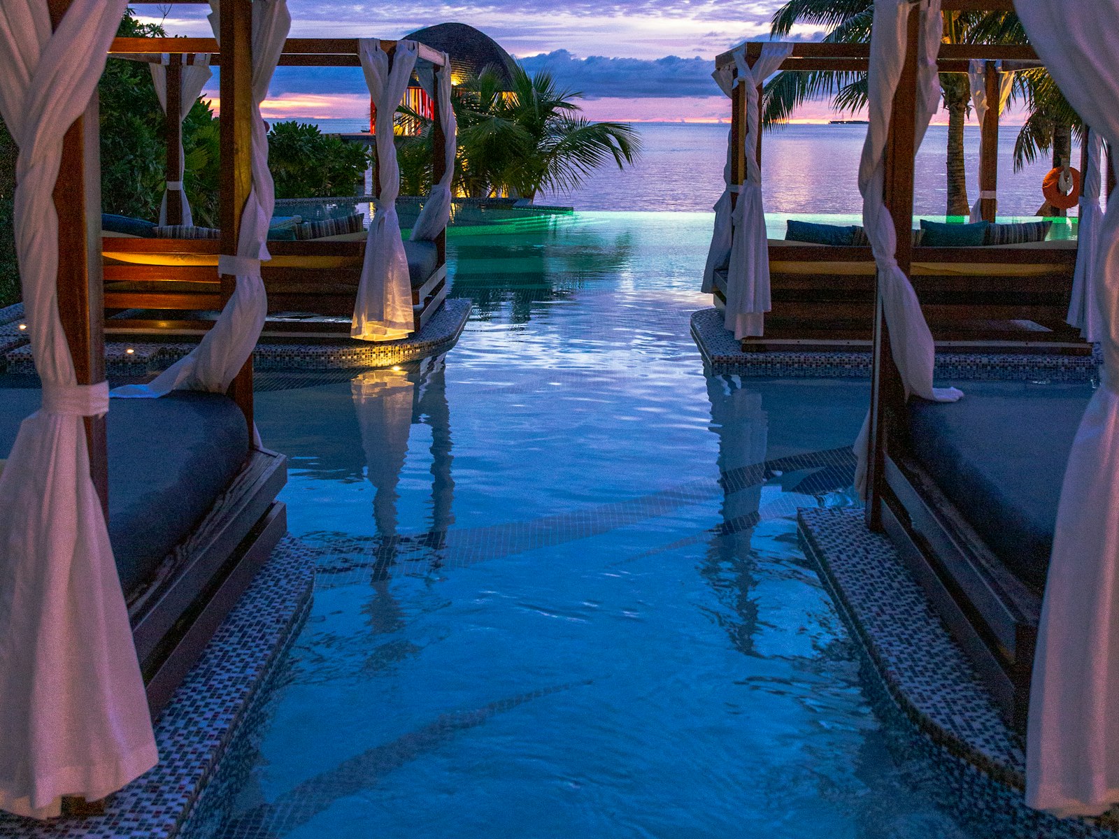 Shaded poolside cabanas within a resort-style courtyard at dusk.